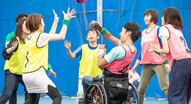 車椅子の選手と子ども、大人が入り混じってボールを追うゆるスポーツの試合風景