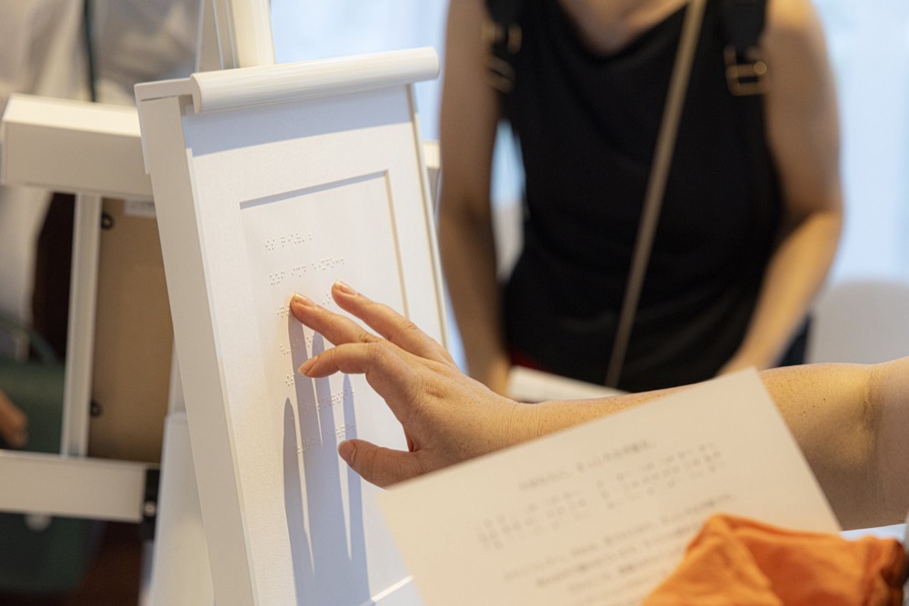 来場者が指先で点字の手紙に触れ、言葉を読み解く様子